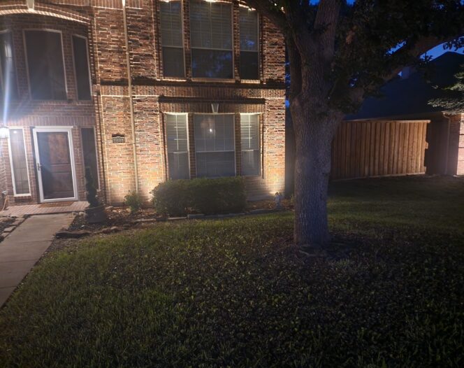 A house at night, brightly lit in the front and back, showcasing enhanced lighting features.